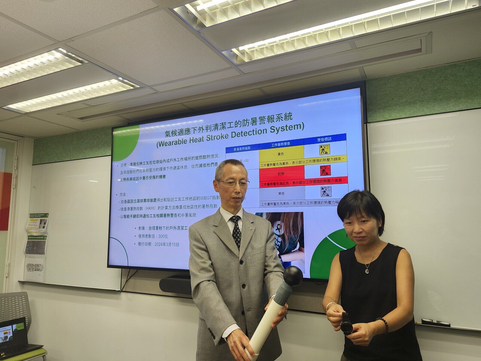 數碼港和香港城市大學HK Tech 300創科公司 - 奧斐康生物有限公司董事羅維堅 及樂施會港澳台項目總監黃碩紅展示黑球濕球(WBGT)裝置及智能暑熱手錶。