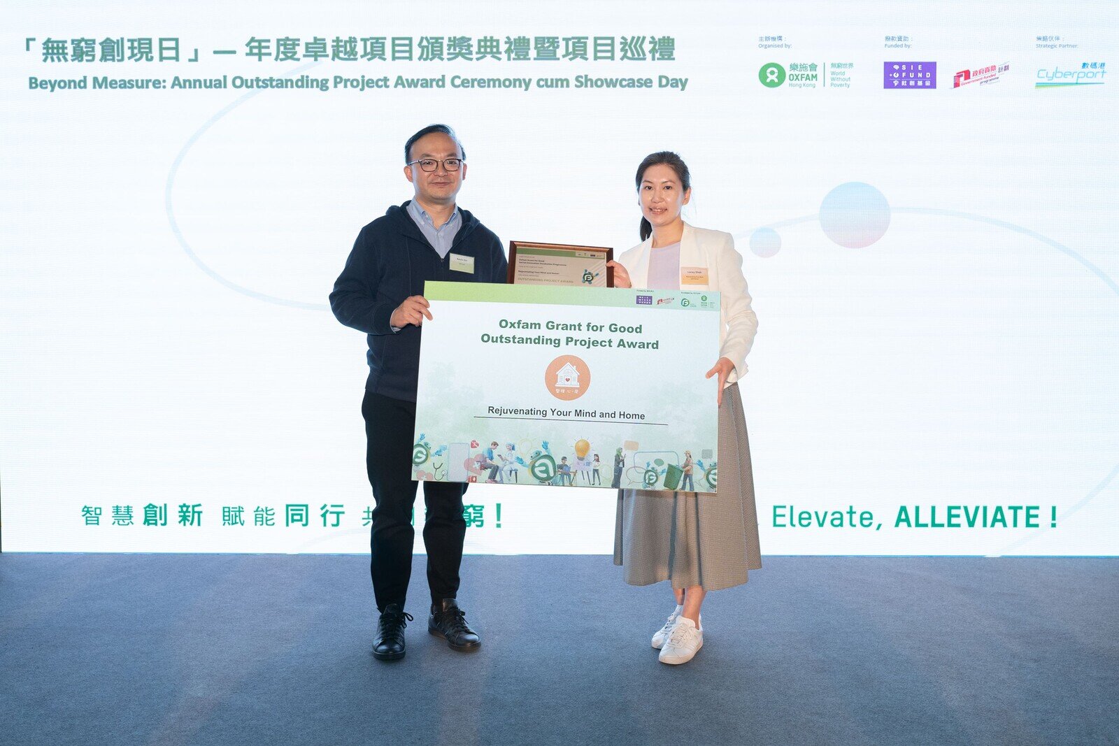 社創基金專責小組主席柯家洋（左）頒發「年度卓越項目獎」獎狀予無窮實現室得獎項目「整理『心．房』」。