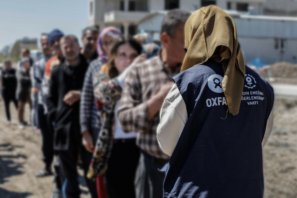 Oxfam staff's back with a line of people in front of her.